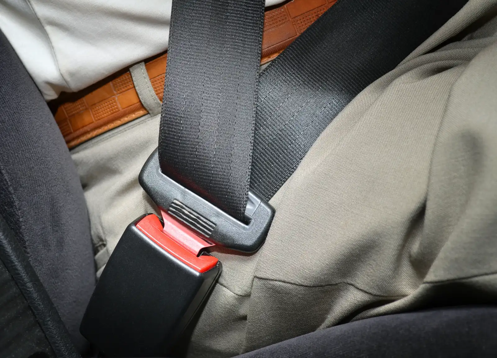 Seat belt webbing and buckle assembly fastened across a seated occupant in a vehicle.
